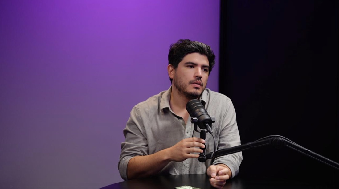 Invitado grabando podcast con iluminación cinematográfica y fondo lila